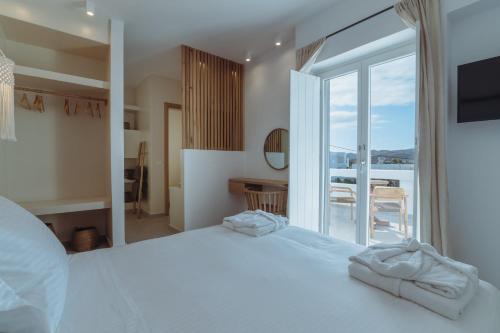 a bedroom with a large white bed and a balcony at Art of Filoxenia with swimming pool in Andiparos