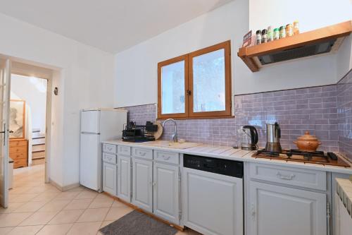 une cuisine avec des armoires blanches et un réfrigérateur blanc dans l'établissement L’Écrin du Brulat - Jardin et vue montagnes, au Castellet