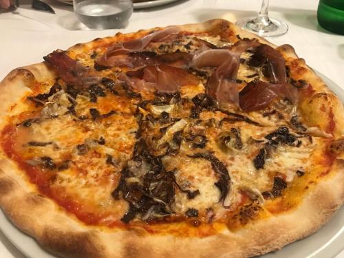 a pizza sitting on top of a white plate on a table at Locanda Al Santuario in Peschiera del Garda
