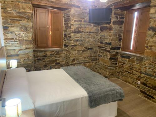 a bedroom with a bed and a stone wall at Apartamentos Casa Benito in San Tirso de Abres
