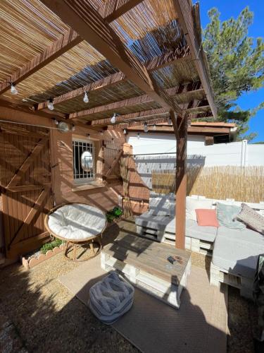 une pergola en bois avec un canapé et une chaise sous celle-ci dans l'établissement Maison de vacance bord de mer, au Barcarès