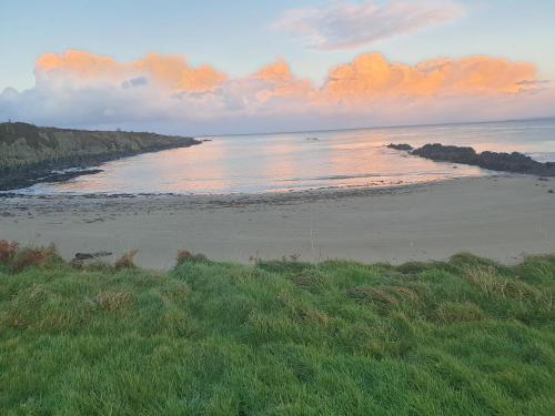 a view of a beach at sunset with the ocean at Sea View Upper Apartment in Greencastle