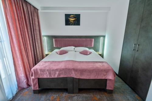 a bedroom with a large bed with a pink blanket at La Borsanu in Năsăud