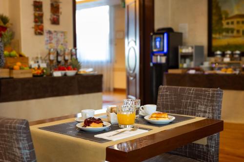 a table with plates of food and orange juice on it at iH Hotels Padova Admiral in Padova