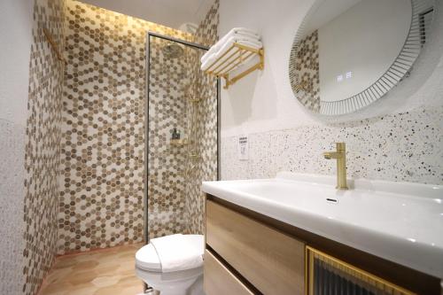 a bathroom with a sink and a toilet and a mirror at Casabella Homestay 301 Batam Penuin in Mantaak