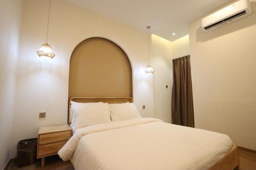 a bedroom with a large white bed with two lights at Casabella Homestay 303 Batam Penuin in Mantaak