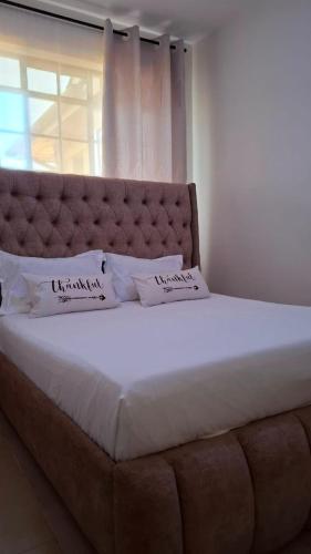 a large bed with two pillows on top of it at Ponton Stays in Eldoret