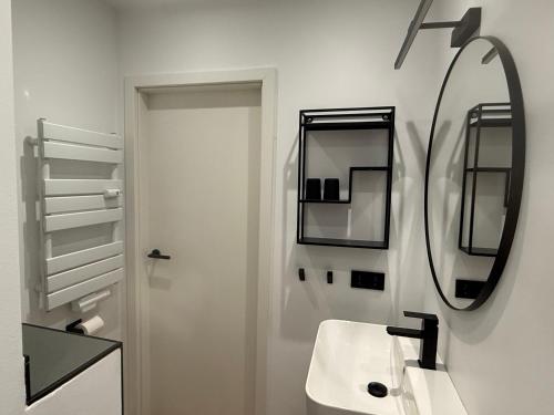 a white bathroom with a sink and a mirror at Panoramablick Ostsee, Binnensee & Salzwiesen - Balkon - Stilvoll - Highspeed Glasfaser WLAN - Parkplatz - Ferienwohnung 'Freiheit' in Heiligenhafen