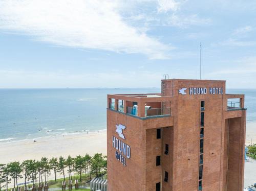 a building at the beach with the ocean in the background at Hound Hotel Deacheon Beach in Boryeong