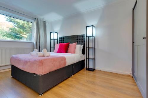 a bedroom with a large bed with pink pillows at Charming Semi-attached bungalow with free parking Pass the Keys in Cambridge
