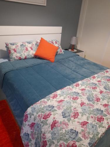 a bed with a blue comforter and an orange pillow at O Cantinho da Auzenda in Torre de Moncorvo