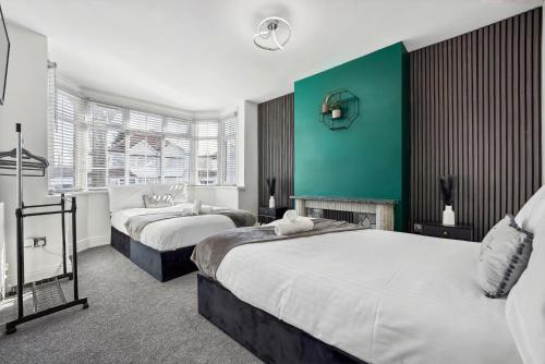 a bedroom with two beds and a green wall at 7 Bedroom Luxury House sleep 26 in Birmingham