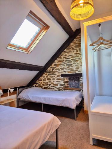 une chambre mansardée avec deux lits et une fenêtre dans l'établissement La Maison Neuve Gîtes, à Madré