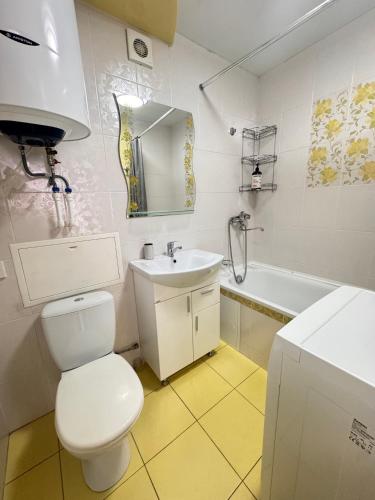 a bathroom with a toilet and a sink and a tub at Apartment on Bukhar Zhyrau in Karagandy