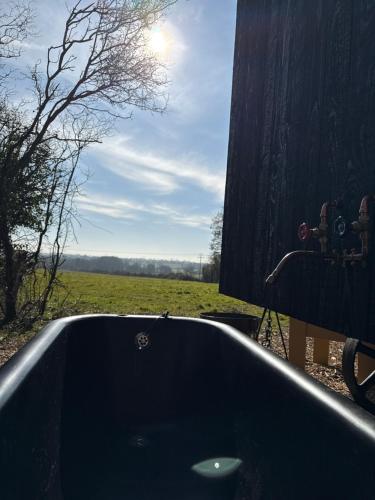 a bath tub with a view of a field at 'Russet' Hut on fruit farm in Charsfield