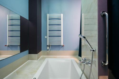 a bathroom with a white tub and a shower at Native Apartments Krupnicza 7 in Kraków