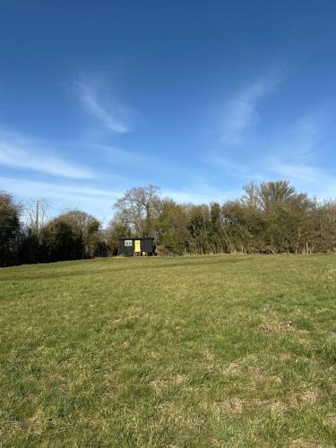 a large field with a building in the distance at 'Russet' Hut on fruit farm in Charsfield