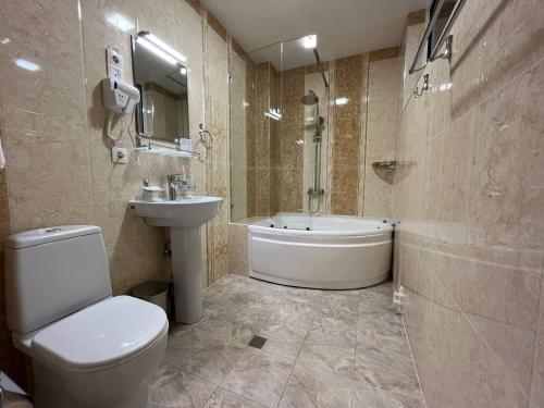 a bathroom with a toilet and a sink and a tub at AKS Hotel in Tashkent