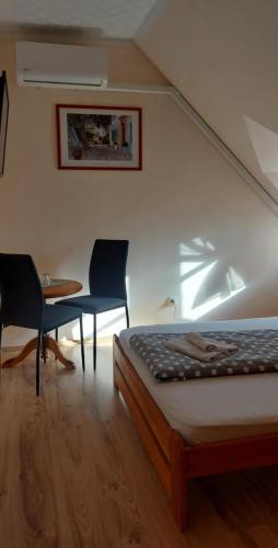 a bedroom with a bed and two chairs and a table at Diána Fogadó in Keszthely