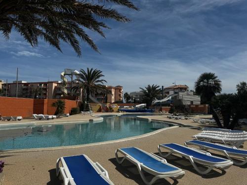 une piscine avec des chaises longues dans un complexe hôtelier dans l'établissement Mobile home Le Badwill2, à Canet