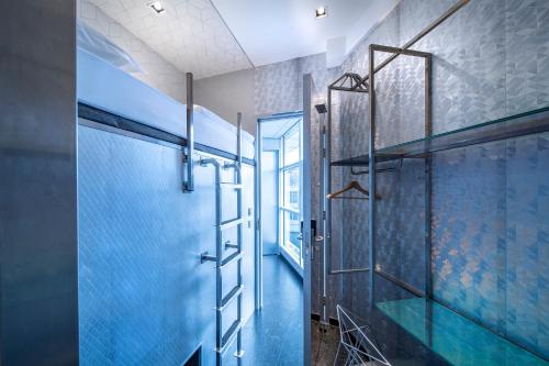 阿姆斯特尔芬Diamond Capsule Hotel Amsterdam South的浴室设有蓝色瓷砖玻璃淋浴间