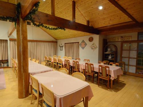 a dining room with tables and chairs and wooden ceilings at Pension Avenue in Yamanakako