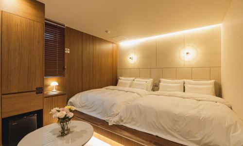 a bedroom with a large white bed and a table at Hound Hotel chuncheon in Chuncheon