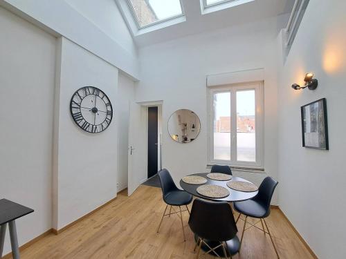 une salle à manger avec une table, des chaises et une horloge dans l'établissement Montevideo - Appartement Lumineux, à Reims