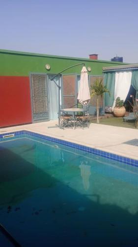 a swimming pool with a table and an umbrella at Keur youngar2 in Gandigal