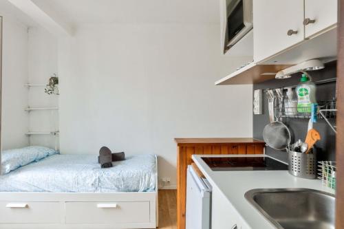 une petite cuisine avec des armoires blanches et un évier dans l'établissement Studio near Père Lachaise Cemetery, à Paris