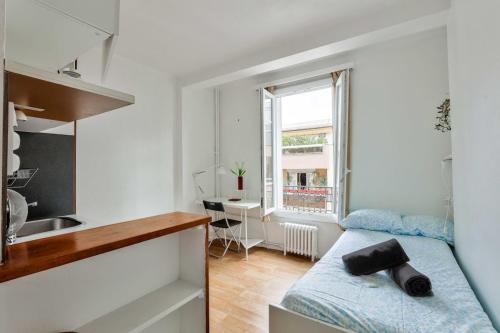 une petite chambre avec un lit et un bureau dans l'établissement Studio near Père Lachaise Cemetery, à Paris