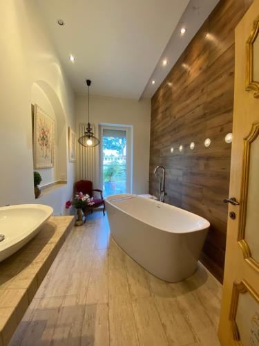 La salle de bains spacieuse est pourvue d'une grande baignoire et d'un mur en bois. dans l'établissement Villa avec piscine, Nice Centre, à Nice