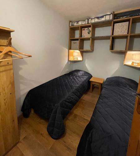 Cette chambre comprend 2 lits et des étagères murales. dans l'établissement Bel appartement T3 pour 6 à 8 personnes à Brides-Les-Bains, à Brides-les-Bains