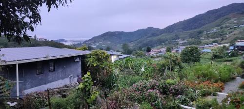 a small house on a hill with mountains in the background at KOMOWANAN HOMESTAY in Kundasang