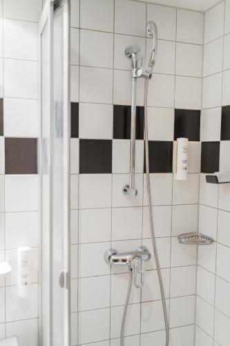 a shower in a bathroom with black and white tiles at Vienna West Business Inn in Vienna