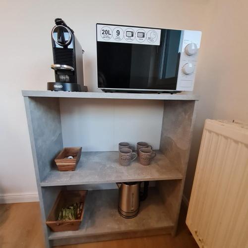 a microwave sitting on top of a shelf with cups at Sarahs Village Apartments in Ottnang am Hausruck