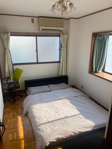 a bed in a bedroom with two windows at 静佳民宿 in Osaka