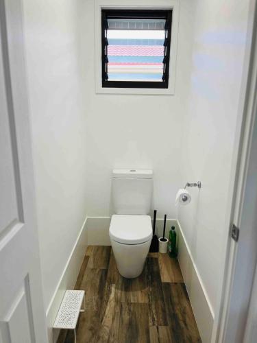 a bathroom with a toilet and a window at OneWorldLove Garden in Woy Woy