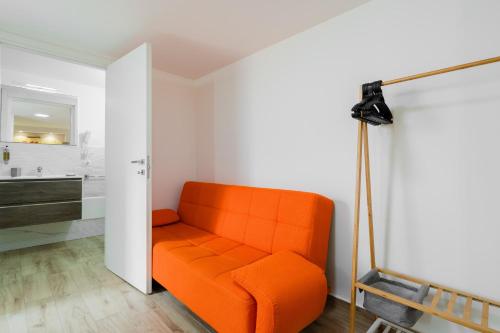 an orange couch in a room with a bathroom at Luxury 12 in Tuglie