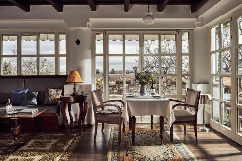 a dining room with a table and chairs and windows at Rókusfalvy Borhotel és Fogadó in Etyek