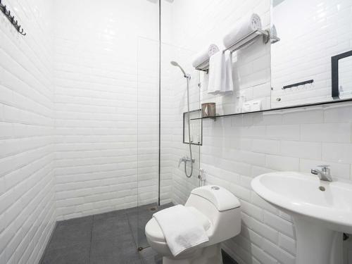 a white bathroom with a toilet and a sink at KYRIAD M2 LAMPUNG in Lampung
