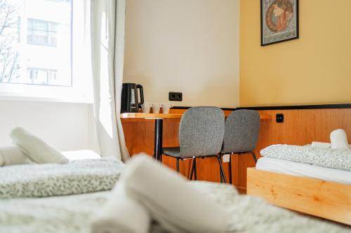 a room with two beds and a desk and two chairs at Vienna West Business Inn in Vienna
