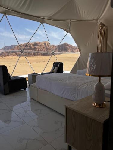 a bed in a tent with a view of the desert at Wadi rum Ali camp in Wadi Rum