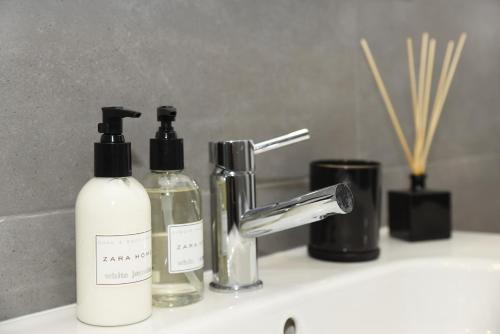 een wastafel in de badkamer met 2 flessen zeep en een kraan bij MyHome Braga1 in Braga