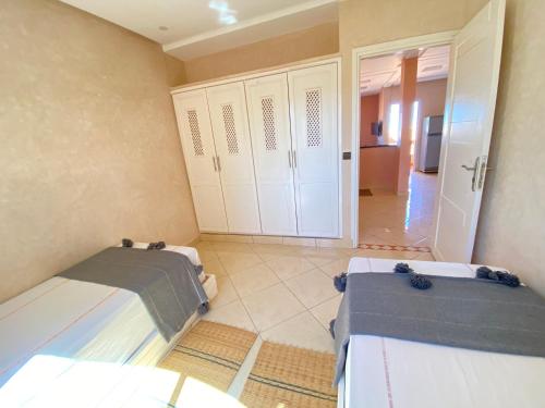a room with two beds and a door to a kitchen at Tawada in Mirleft