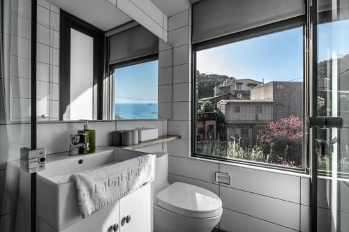a bathroom with a sink and a toilet and a window at Jiufen Ore Inn in Jiufen