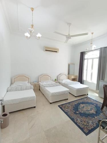 three beds in a white room with a rug at Leyla Hostel in Mawāliḩ