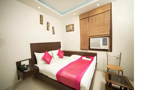 a bedroom with a large bed with pink pillows at Hotel Sunrise DX in New Delhi