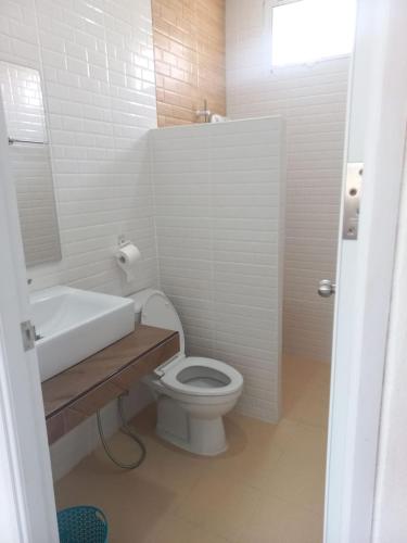 a white bathroom with a toilet and a sink at บ้านสวนสุรัชฎา ปาย in Kampong Huaibū