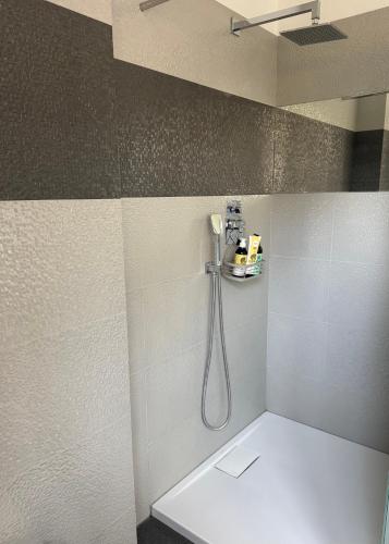 a bathroom with a shower with a hose on the wall at Apartament nad jeziorem in Barlinek